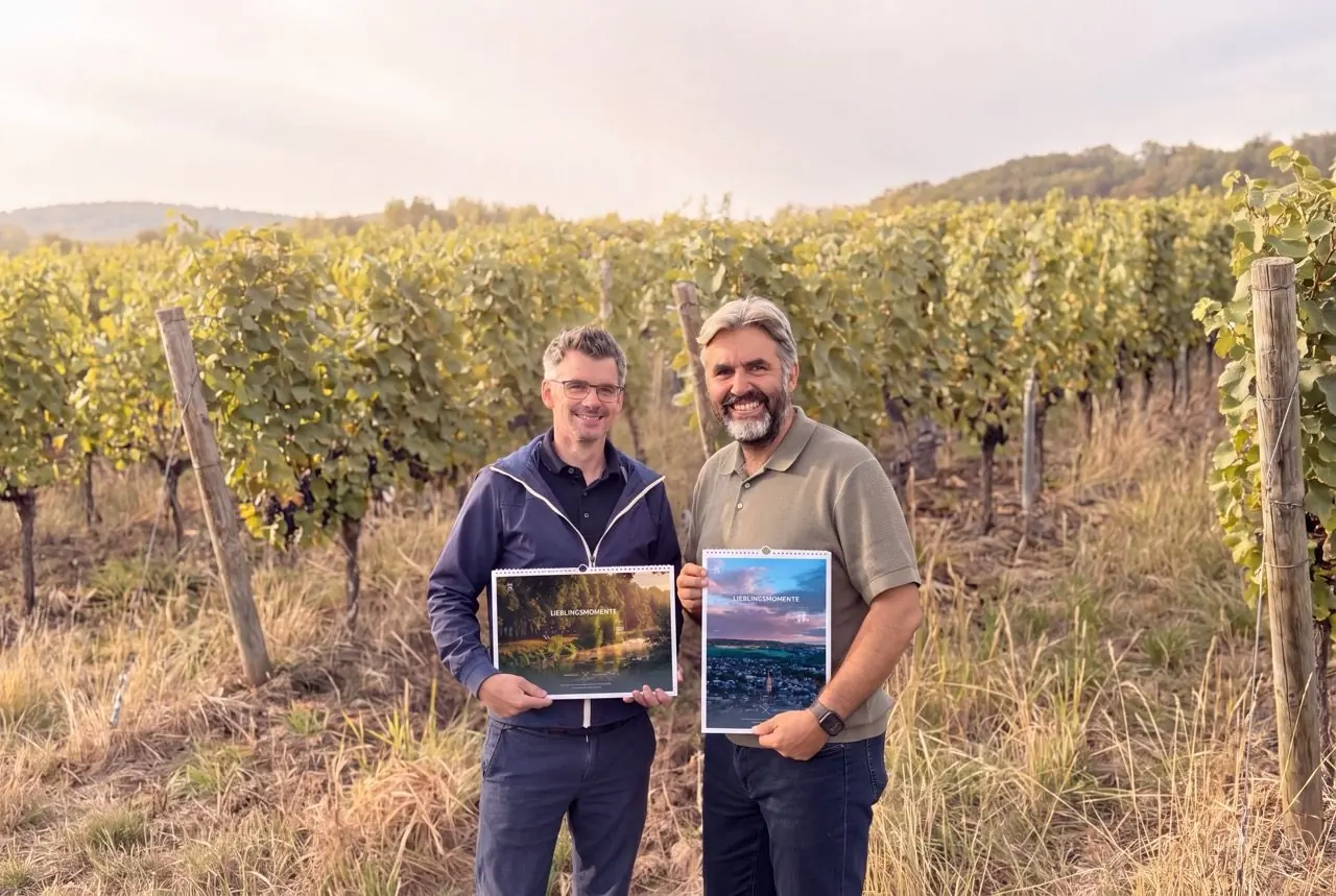 Dominik Ketz und Kai Schneiders halten die beiden Titelbilder des Kalenders in den Weinbergen